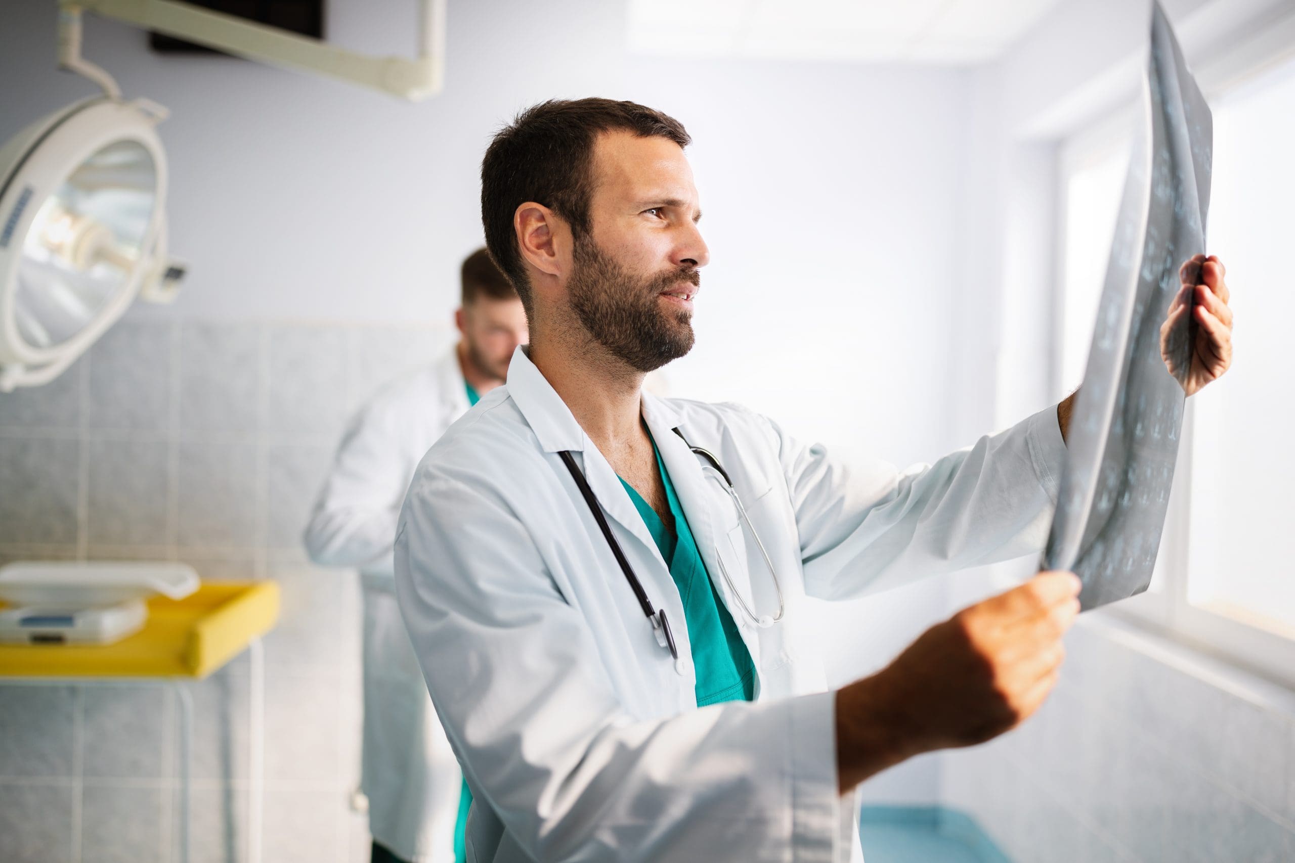 Portrait of handsome young doctor checking X-Ray in hospital to make diagnosis