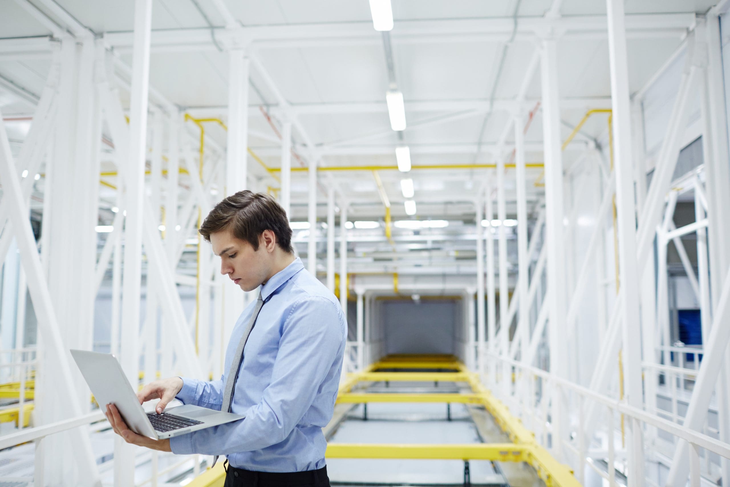 Young specialist with laptop browsing in the net during work in mining farm